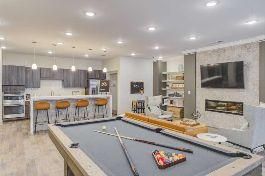 Apartment clubhouse with pool table, breakfast bar, and seating area with TV.